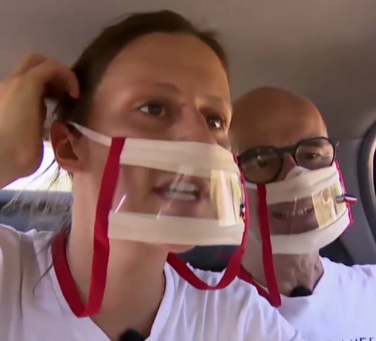 Photo de Christophe et Claire le duo père fille de Pékin Express ici dans une voiture pendant l'émission. On les voit porter des masques sourire rouge d'Odiora